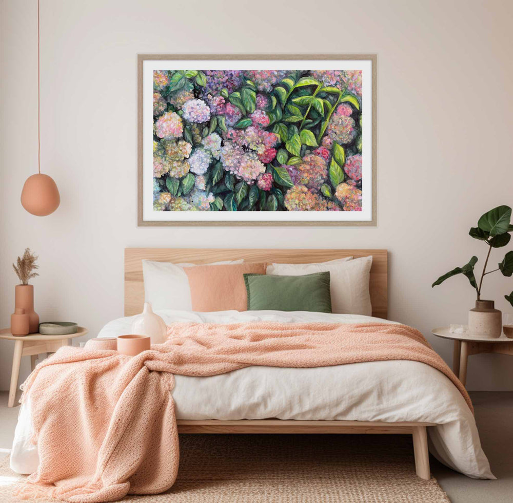 A framed art print of colorful hydrangeas displayed on a wall above a bed in a bedroom setting.